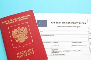 Schengen visa application form in Swedish language and passport on blue background. Prohibition and suspension of visas for Russian tourists to travel to European Union and the Baltic States concept