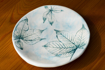 Handmade light blue ceramic plate with decorative prints of decorative 