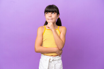 Little caucasian kid isolated on purple background having doubts and thinking
