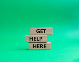 Get help here symbol. Wooden blocks with words Get help here. Beautiful green background. Business and Get help here concept. Copy space.