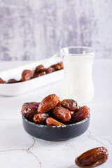 Dates in a bowl and a glass of milk on the table. Food for the holy month of Ramadan. Vertical view