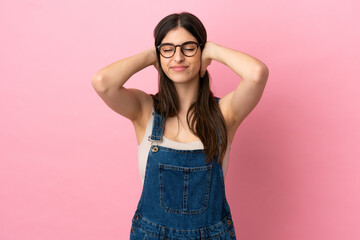 Young caucasian woman isolated on pink background frustrated and covering ears
