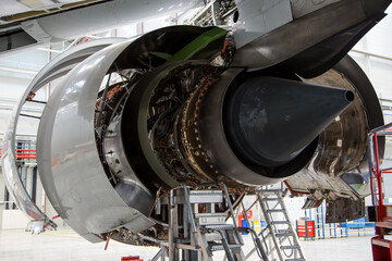 Engine of passenger jet aircraft closeup. The hoods is open. Back view - nozzle.