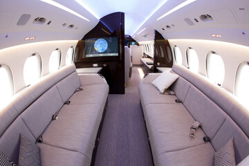 Luxurious interior of a business jet. Soft sofas, pillows, screens of on-board entertainment system.