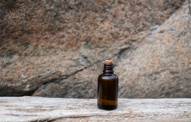 Small brown glass medicine bottle on aged wood background. Essential oil. 
