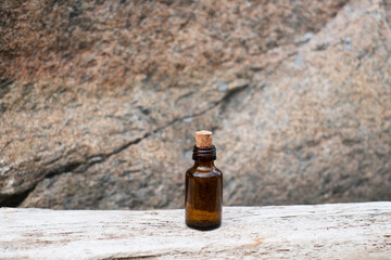 Small brown glass medicine bottle on aged wood background. Essential oil. 