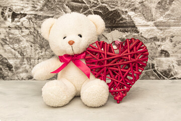 White Teddy bear with red heart on grey wall background