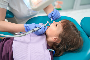 Dental hygienist conducting teeth-polishing procedure on little girl