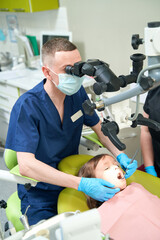 Professional pedodontist examining teeth of female child