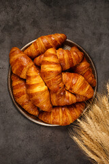 crispy croissants on a large tray on a gray background, top view
