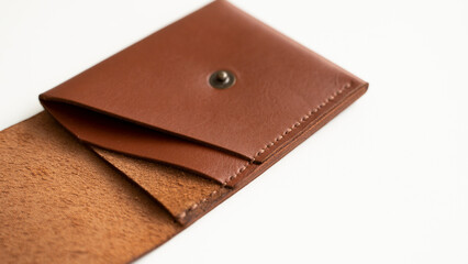 Opened empty orange genuine leather card holder on a white surface.
