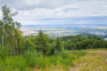 Fototapeta na wymiar Rural Russian landscape with Belokurikha town on a background