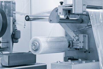 Automatic polyethylene plastic bag production machine with lighting effect. Close-up of the roller of the plastic bag production machine in the light blue scene. product packaging concept