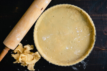 Tart Pan Filled with Raw Pastry Dough: Dough-filled tart pan with pastry crust scraps and a rolling pin