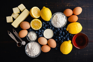 Blueberry–Lemon Curd Tart Raw Ingredients on a Wood Table: Fresh blueberries, lemons, and other uncooked ingredients on a dark background