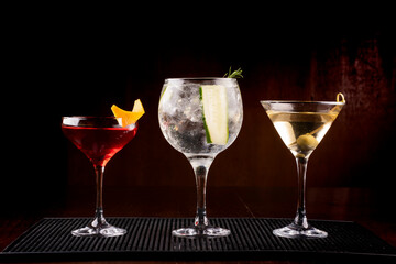 collection of three cocktail glasses including gin tonic martini and vesper with olive in rubber holder viewed from the front