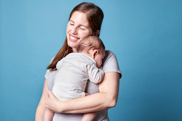 Mother holding newborn baby isolated blue background