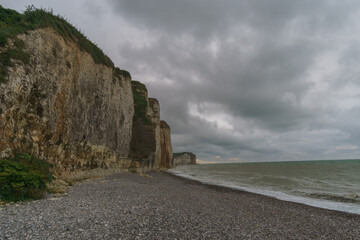 White and brown colored rock cliffs on the Alabaster Coast on a stormy cloudy summer day near Petites-Dalles, Normandy, France