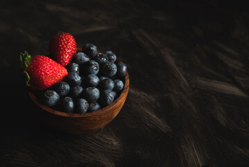 fresas y arandanos en bowl de madera