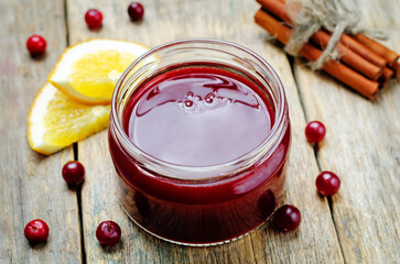 Orange cinnamon honey cranberry sauce in a jar on a wood background