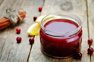 Orange cinnamon honey cranberry sauce in a jar on a wood background