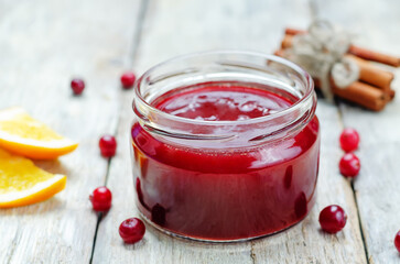 Orange cinnamon honey cranberry sauce in a jar on a wood background