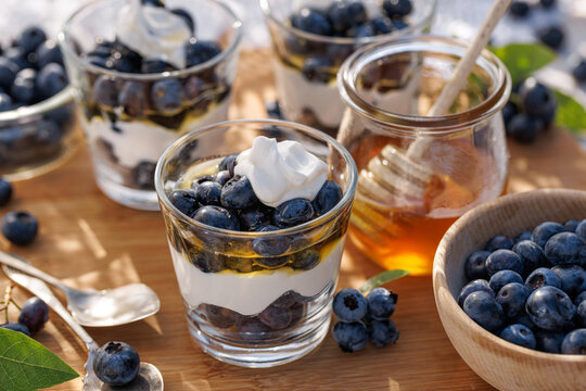 Healthy breakfast, layered dessert made of natural yogurt, fresh blueberries and honey, close-up