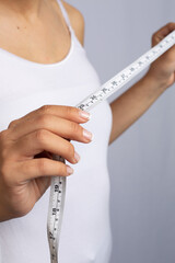 thin woman in white shirt taking her body measurements