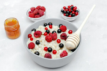 Oatmeal porridge with summer raspberry, currant berries,honey. Porridge oats in bowl with fruits. Healthy food breakfast,lifestyle,dieting, proper nutrition.Top view flat lay on gray table background