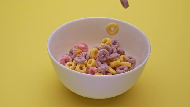 Bowl with multi-colored cornflakes slowmotion
