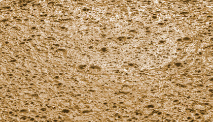 Beige background, dried liquid paint, construction waste. Selective focus. Liquid mud, faeces. Small craters in clay soil. Background created by nature