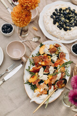 dish with sliced peaches, figs, mozzarella pieces, arugula and prosciutto slices. gourmet snacks for picnic top view