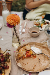 leftover tomato pie on a platter with crumbs. details of a picnic table with food. two slices of tomato galette on a plate