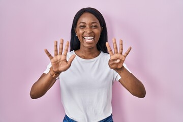 African young woman wearing casual white t shirt showing and pointing up with fingers number nine while smiling confident and happy.