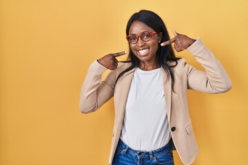 African young woman wearing glasses smiling cheerful showing and pointing with fingers teeth and mouth. dental health concept.