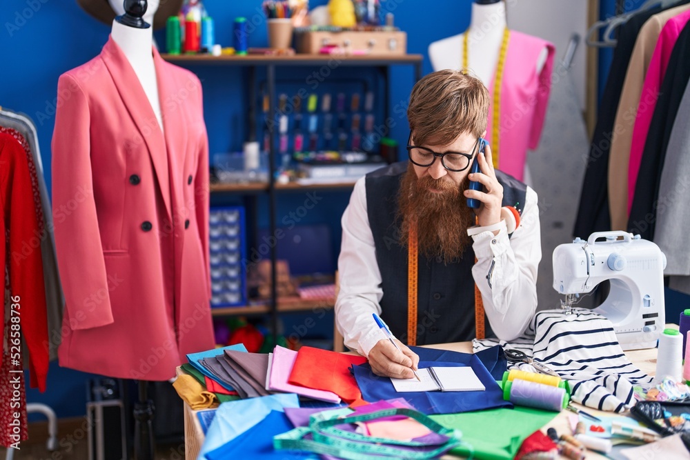 Sticker young redhead man tailor talking on smartphone writing on notebook at clothing factory