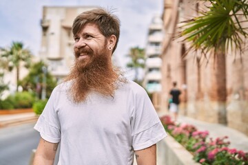 Young redhead man smiling happy standing at the city.