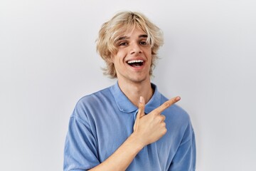 Young modern man standing over isolated background cheerful with a smile of face pointing with hand and finger up to the side with happy and natural expression on face