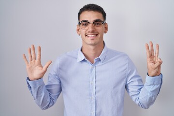 Handsome hispanic man wearing business clothes and glasses showing and pointing up with fingers number eight while smiling confident and happy.