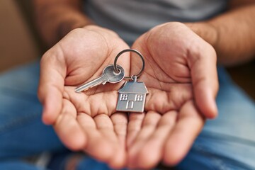 Young hispanic man holding key of new house at new home