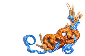 Oktoberfest concept - pretzels with traditional pattern ribbon and ears wheat isolated on white