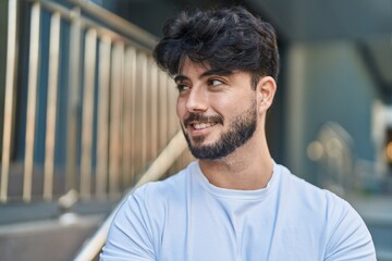 Young hispanic man smiling confident looking to the side at street