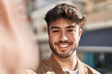 Young hispanic man smiling confident make selfie by camera at street