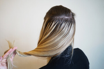 Hair extensions procedure. Hairdresser does hair extensions to young girl, blonde in a beauty...