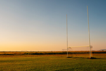 Tall goal posts for Irish National sports in a field of a park at sunrise. Rugby, hurling, camogie and Gaelic football training ground. Nobody. Calm warm color. Dramatic sky. © mark_gusev