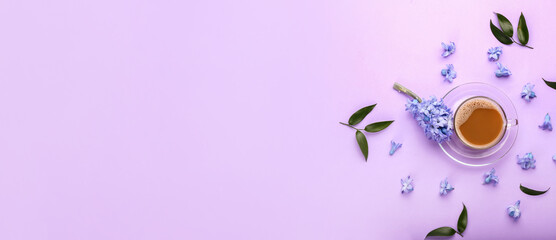 Cup of coffee with spring flowers on lilac background with space for text, top view