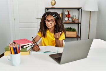 Young african american girl doing homework at home doing money gesture with hands, asking for...