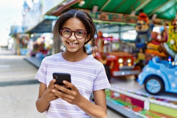 African american girl smiling happy at the town fair using smartphone