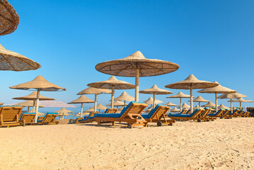 Beach with sunbeds, umbrellas and yellow sand.