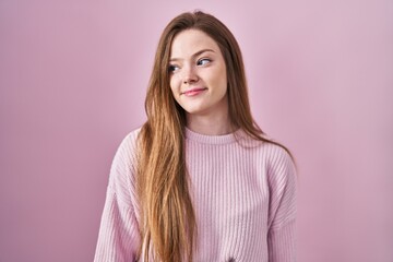 Fototapeta premium Young caucasian woman standing over pink background smiling looking to the side and staring away thinking.